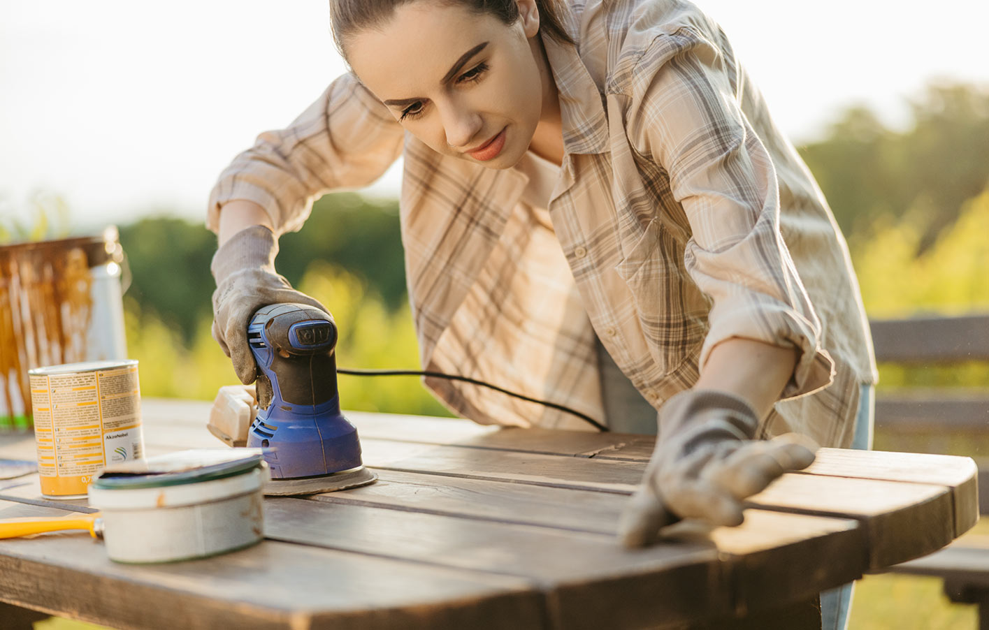 Werterhalt von Holz – nachhaltig und ressourcenschonend - Vorbehandlung Junge Frau schleift Holztisch ab