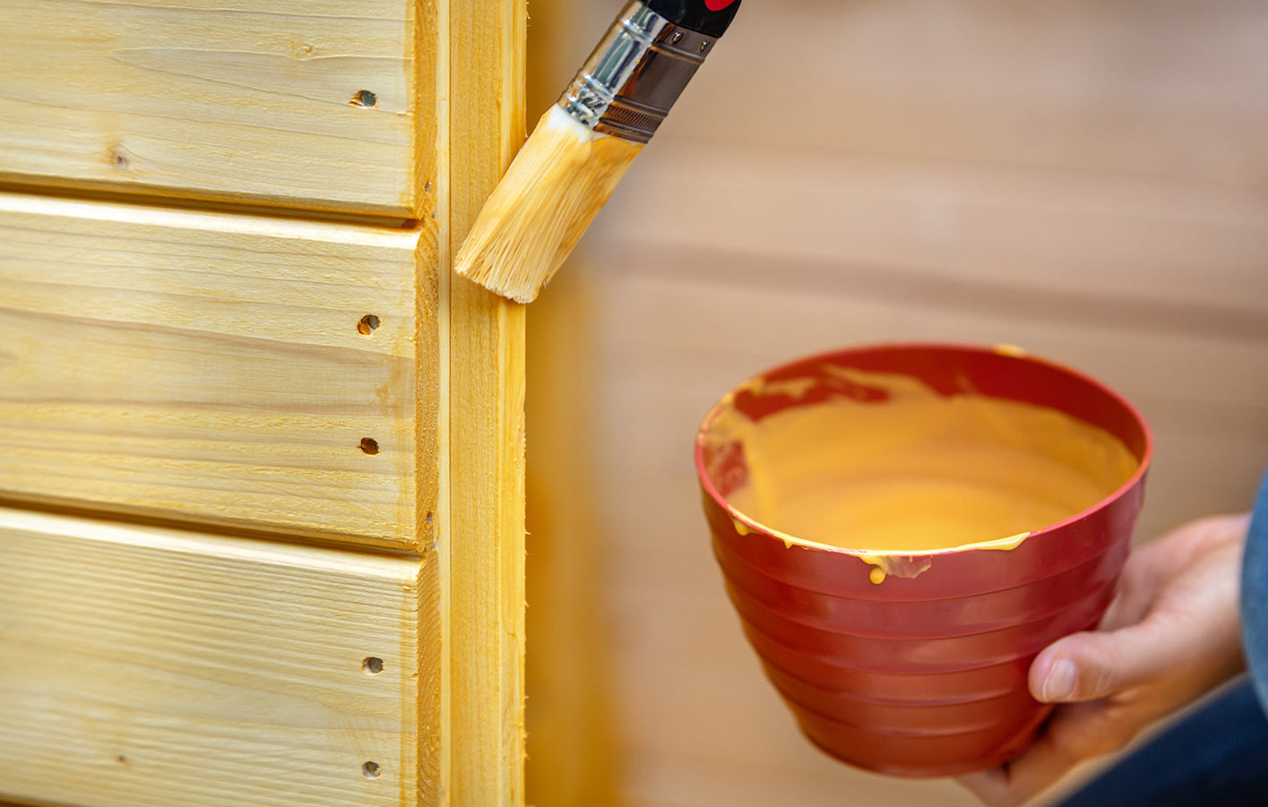 Fichten holz pflegen für eine längere Haltbarkeit Eine Fichtenholzwand wird mit einem pflegenden Anstrich bepinselt
